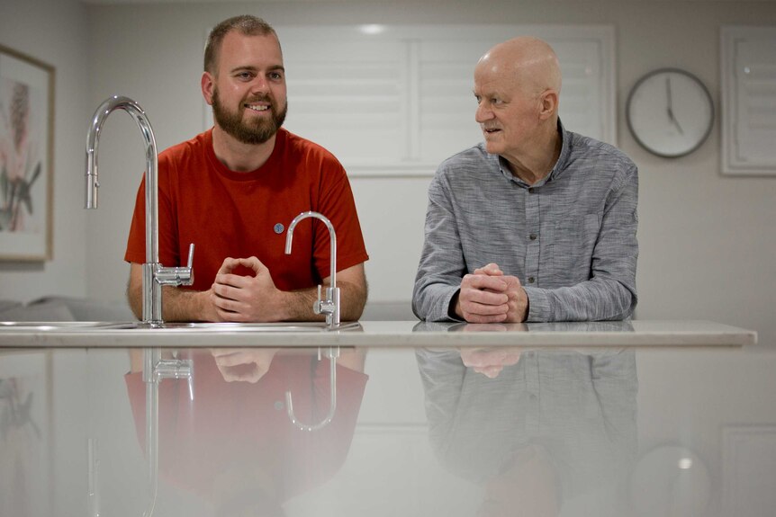 Corey Cook sits alongside his father Stephen at a kitchen bench at the Cook family home in Penrith.