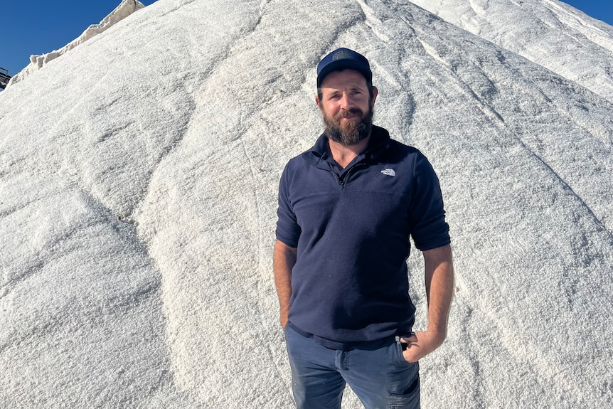 Travis Robinson stands in front of the large piles of washed salt