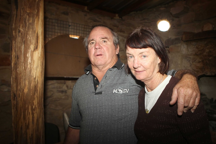 Alan and Chris are standing in an out-house made from stone.