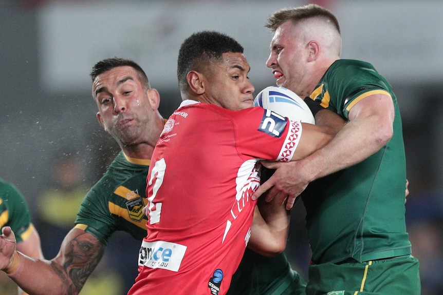 David Fusitu'a of Tonga runs into the tackle of Australia's Cameron Munster and Paul Vaughan.