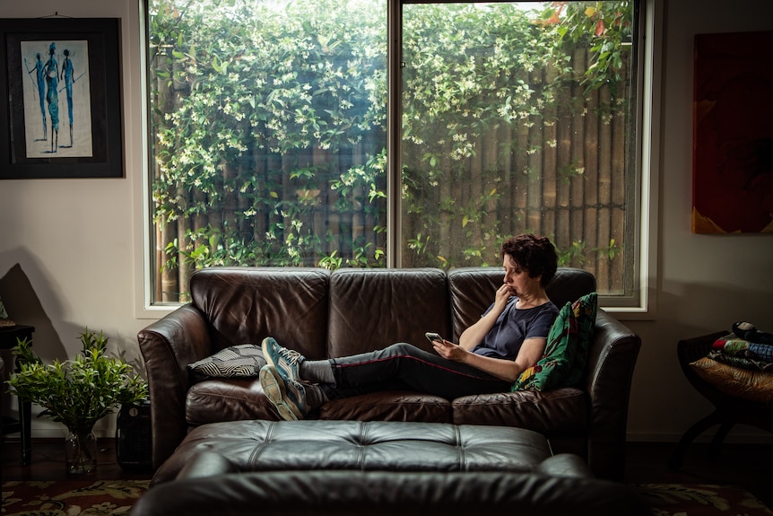 A woman laying down on a couch looking pensive