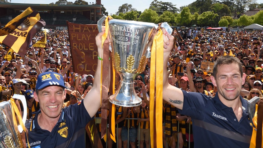 Hawthorn coach Alastair Clarkson and skipper Luke Hodge hold up the premiership cups at Glenferrie.