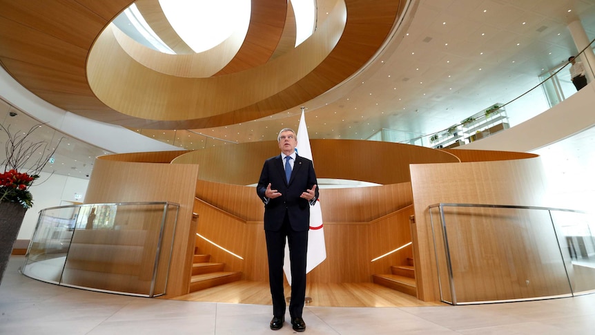 A man in a suit stands in front of an expensive corporate artwork