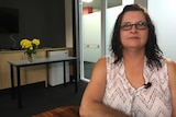 Tracey Hyde sitting at a table wearing reading glasses