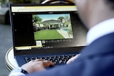 A man in a suit on a laptop searching real estate websites.