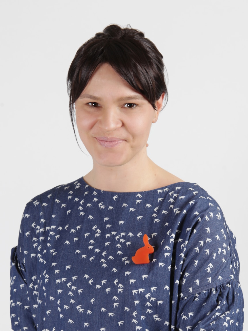 Portrait of a middle-aged woman wearing a blue polka-dot top and red rabbit brooch. 