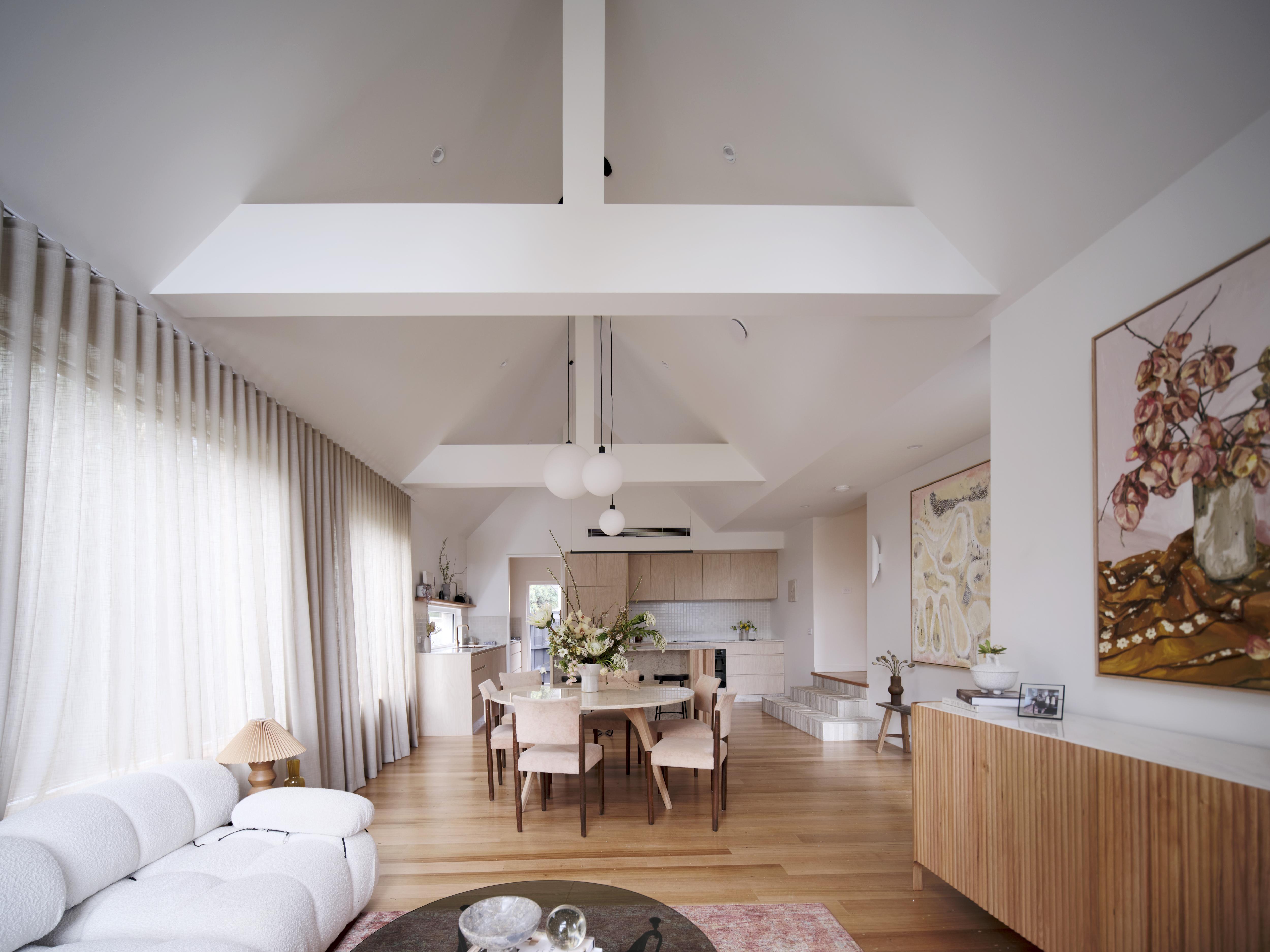 A long shot of a light filled loungeroom with a-frame supports in the ceiling
