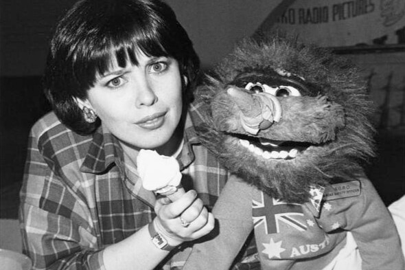 Black and white image woman holding an ice cream next to a scruffy puppet named Agro