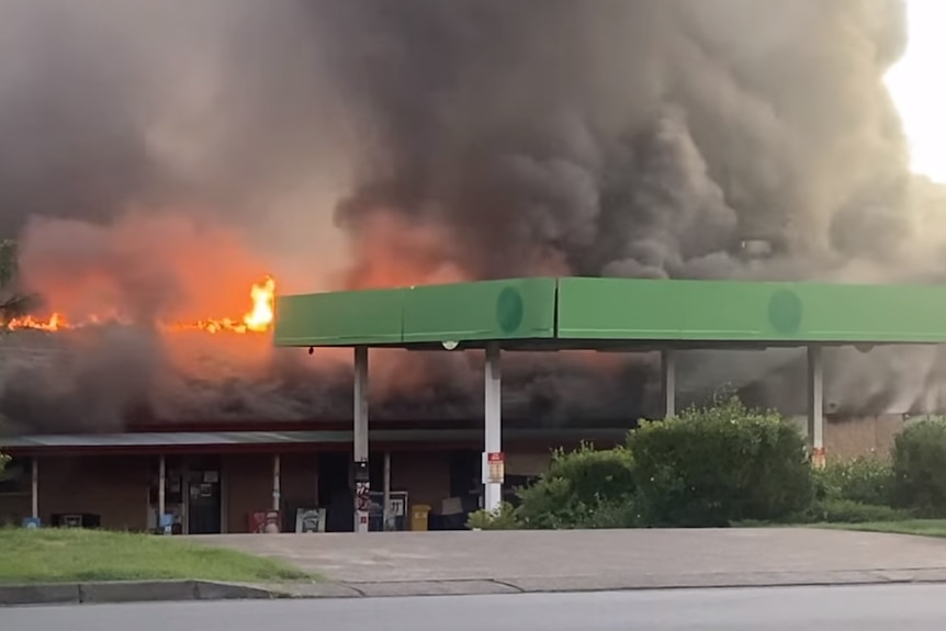 Petrol station surrounded by lots and lots of smoke and a few orange flames