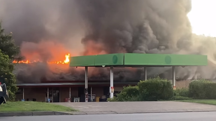 Petrol station surrounded by lots and lots of smoke and a few orange flames