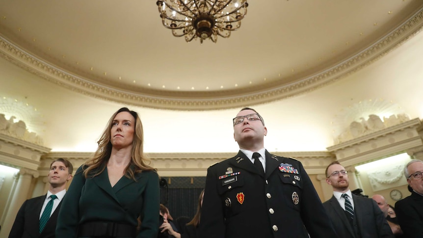 Jennifer Williams, wearing a green dress, stands next to Lt. Col. Alexander Vindman, wearing a uniform.