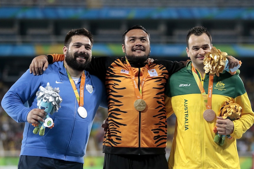 An Australian shot putter stands on the podium with his bronze medal at the Rio Paralympics.