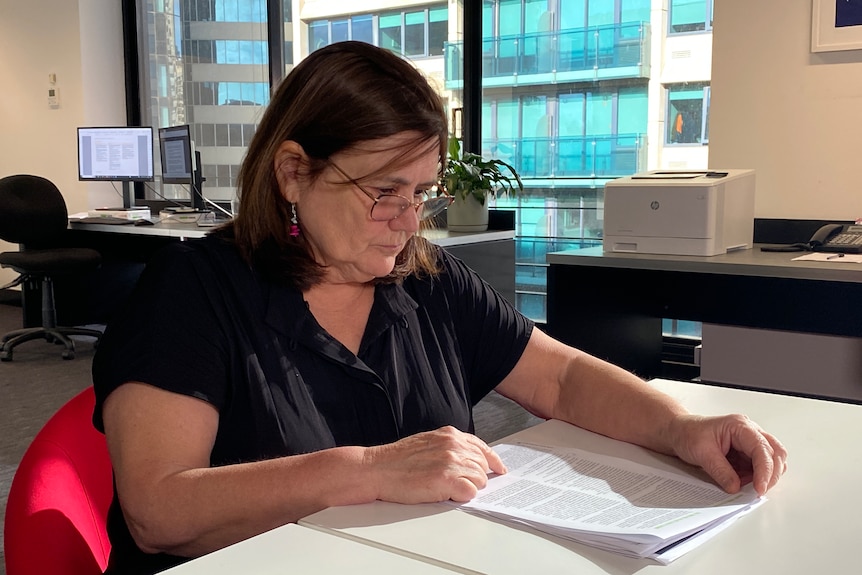 a woman in an office looking at documents 