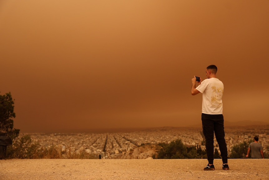 Man takes picture of dust storm in Athens, Greece.