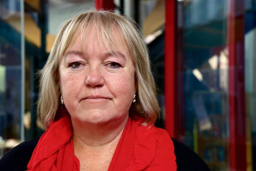 A woman in a red scarf looks at the camera.