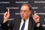 A man points upwards with both hands as he speaks