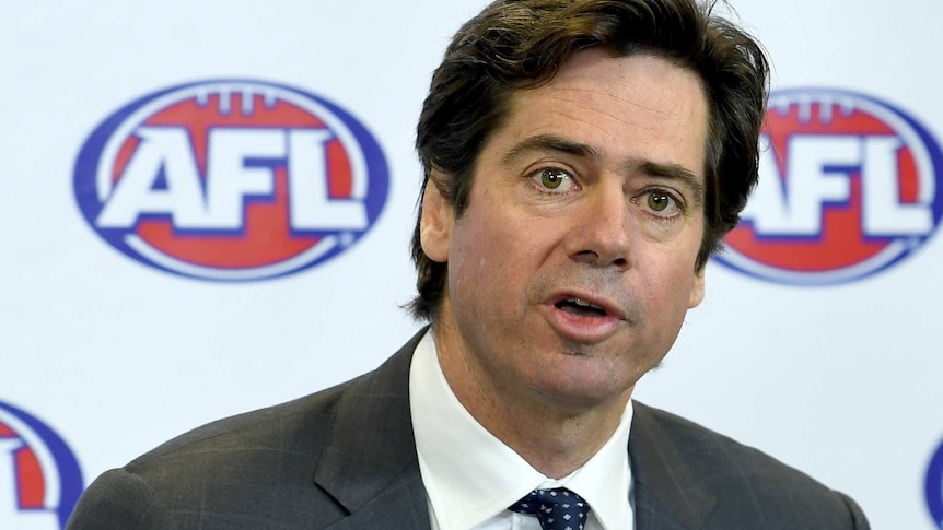 AFL CEO Gillon McLachlan speaks during a media conference in front of a white, red and blue backdrop with the AFL logo on it.