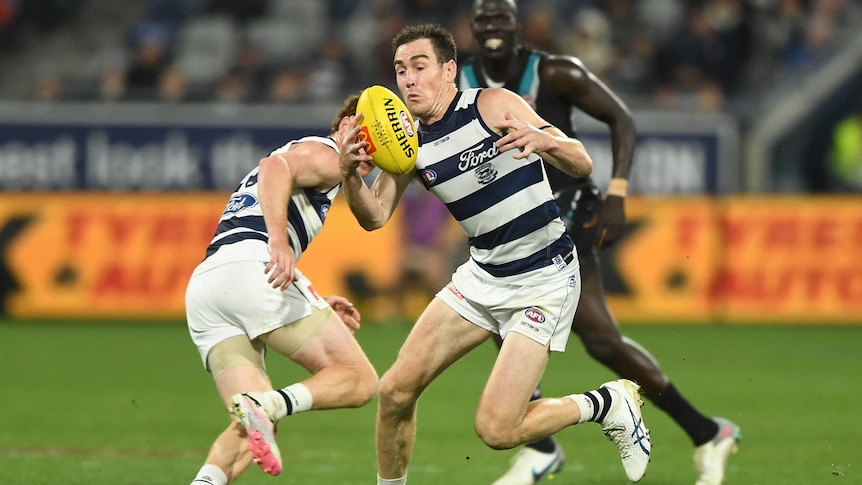 Geelong forward Jeremy Cameron tries to handle the football. It is night