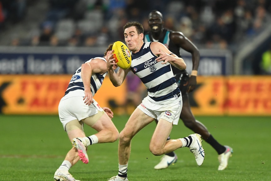 Geelong forward Jeremy Cameron tries to handle the football. It is night