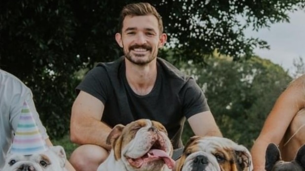 a man smiling with four bulldogs