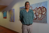 Les Turner stands in front of a blue painting
