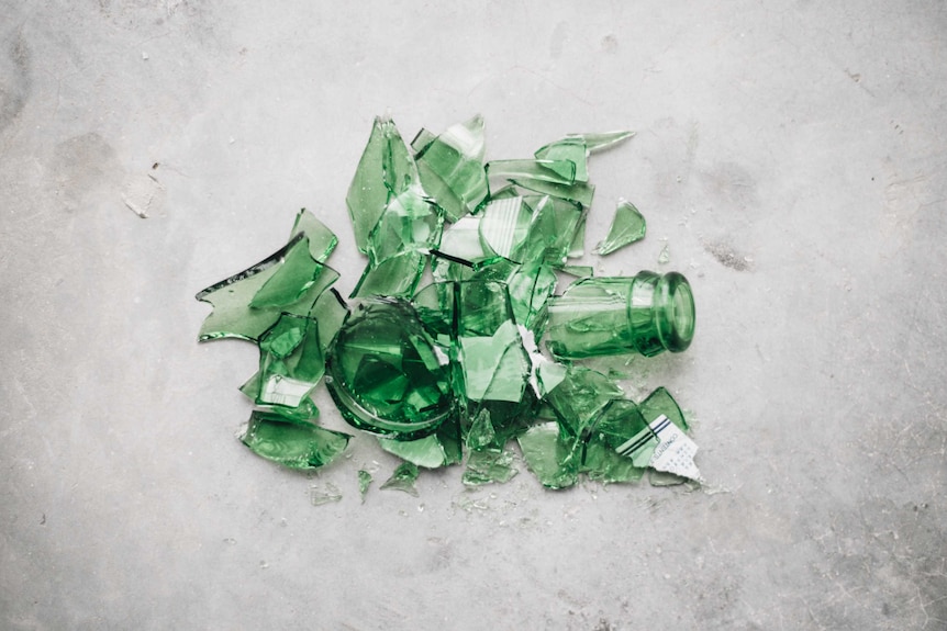 A smashed green glass bottle on concrete