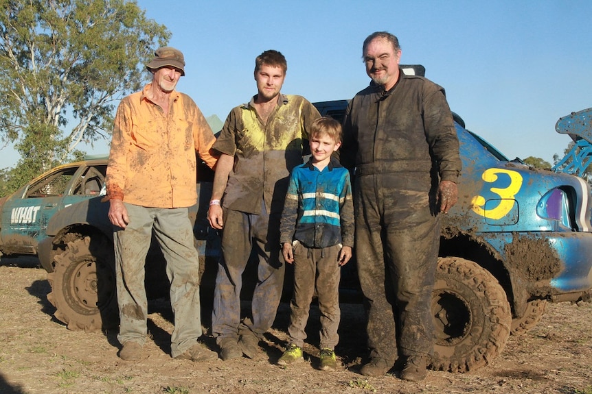 a family covered in mud in front of a car