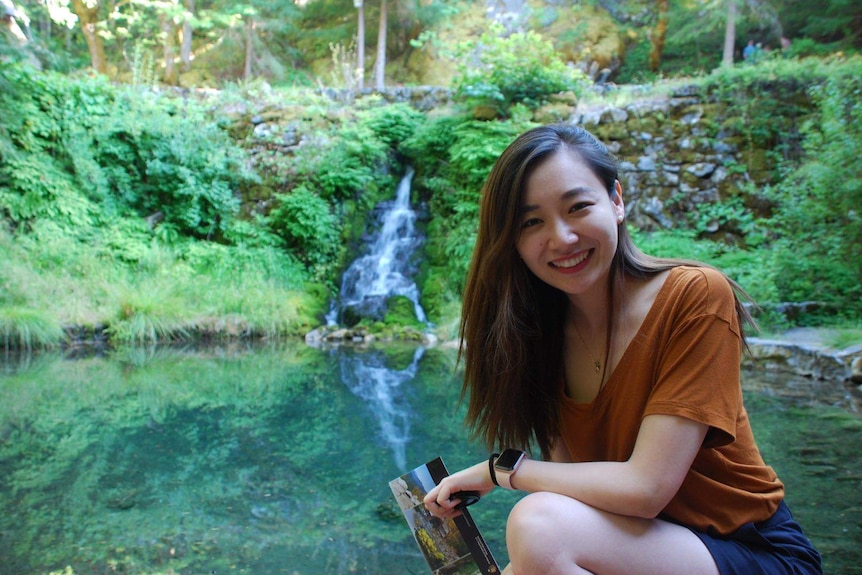 美国华人教师钟珺骅蹲在一团池水旁。