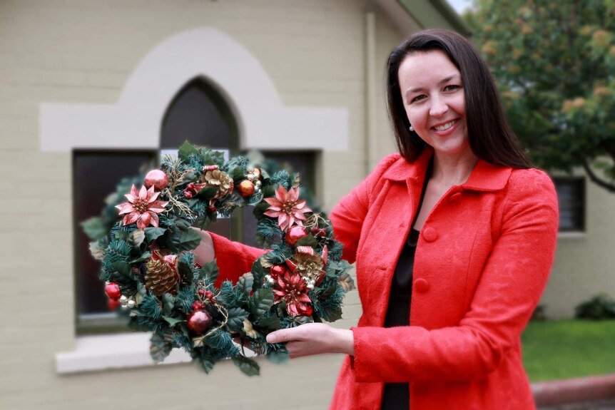 A woman holds a Christmas wreath