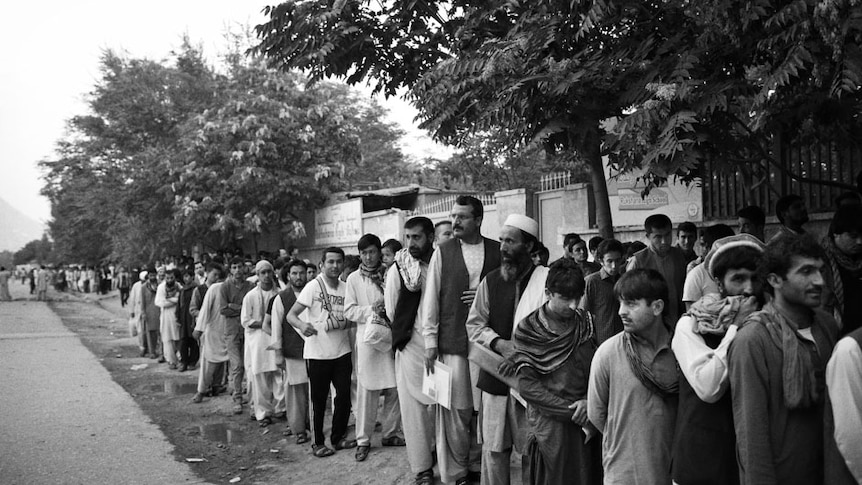 Documents in hand, hundreds of Afghan passport applicants queue before sunrise outside Afghanistan's only passport office.