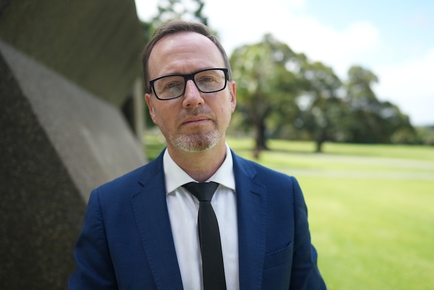 a man in suit and glasses looking firm outdoors