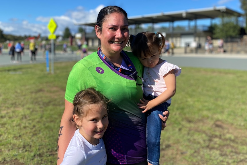 A woman in a triathlon suit with her two young daughters