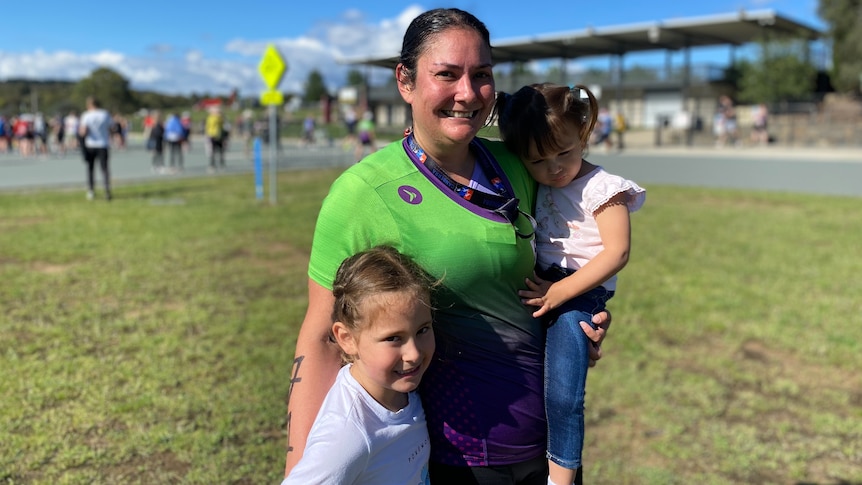 A woman in a triathlon suit with her two young daughters