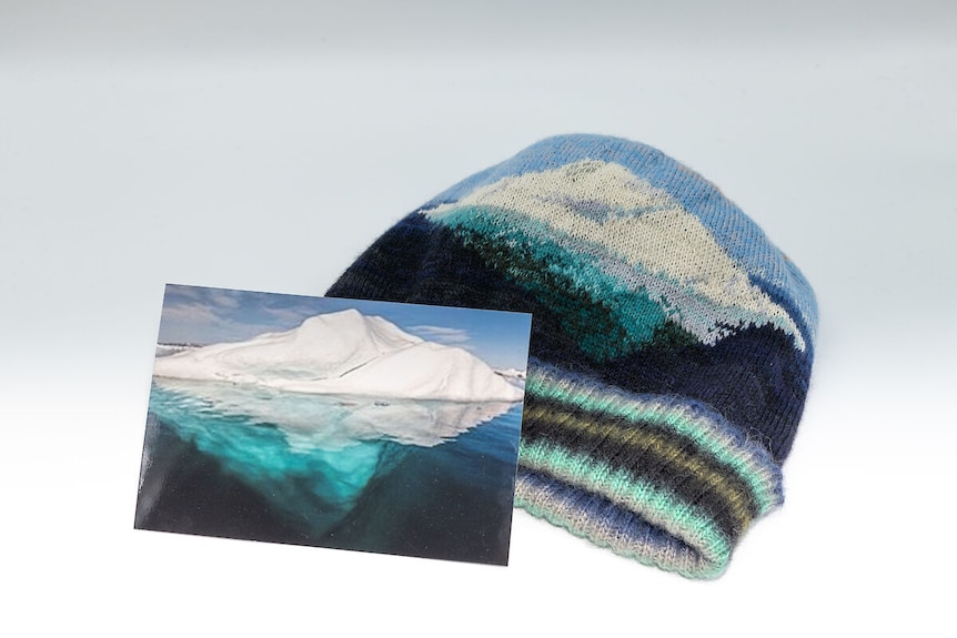 A photo of an iceberg, next to a knitted beanie with an iceberg design.