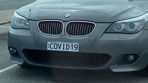 A car with a cover partially covering it in a car park