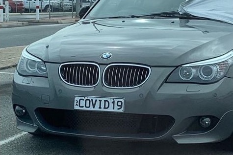 A car with a cover partially covering it in a car park