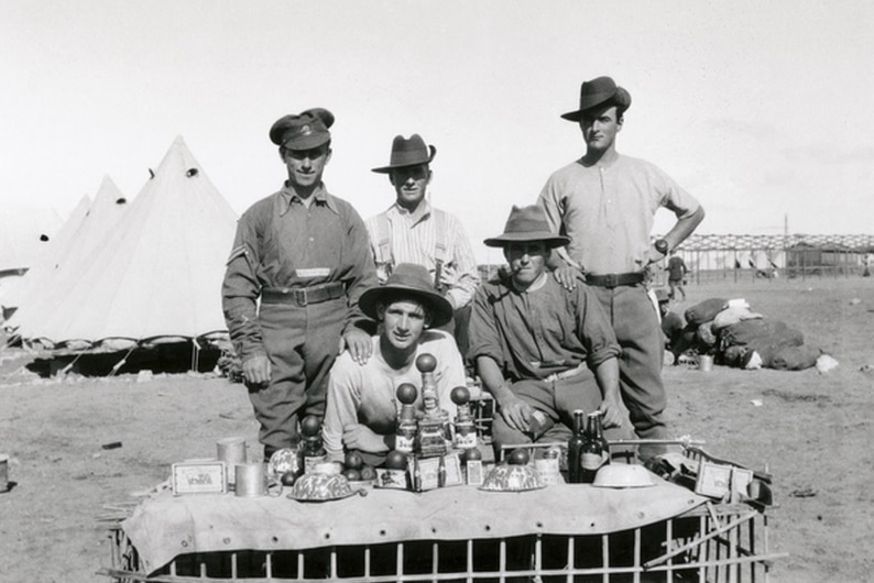 A group of WWI soldiers at an outdoor table with food on it