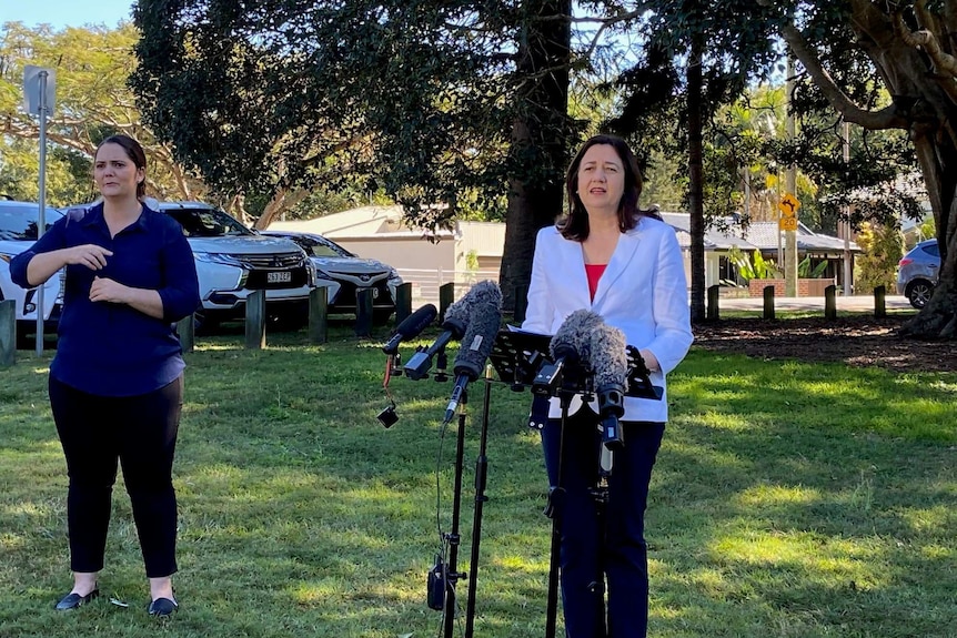 Annastacia Palaszczuk at a park speaking to the media with microphones around her at a lectern.