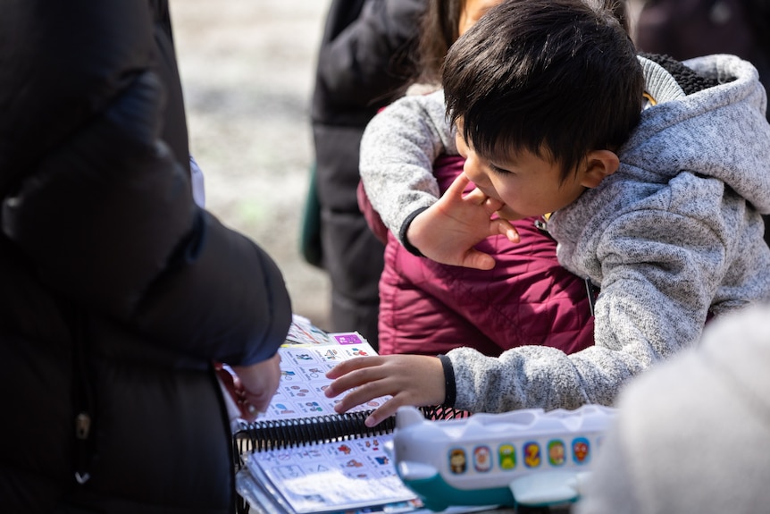 A ten-year-old boy looks at a booklet that mimics images in an AAC device