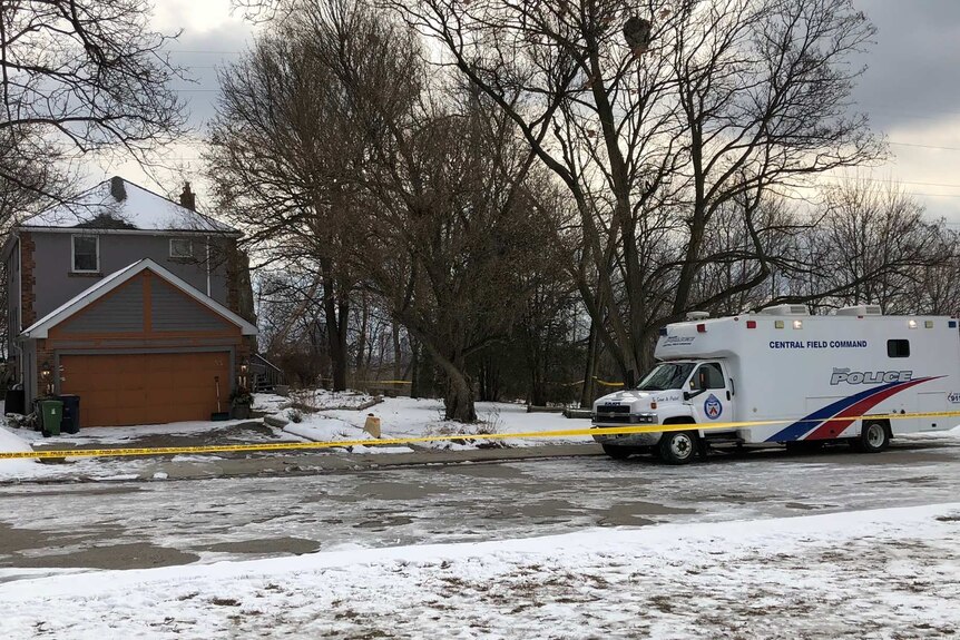 Wide shot of a police truck parked in front of a house in a snowy landscape.