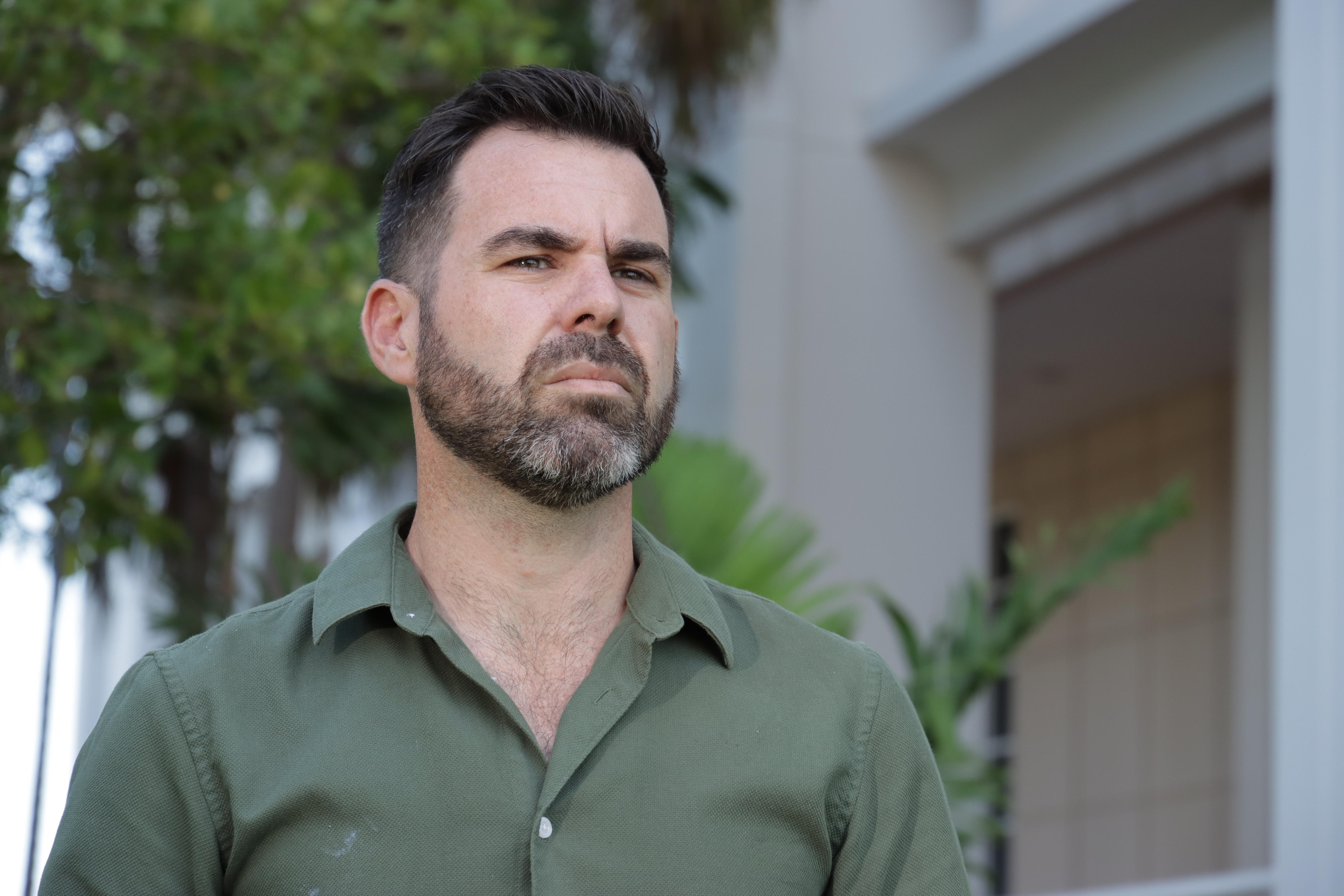 A man standing outside NT Parliament House and looking serious. 