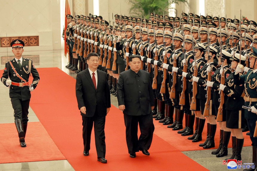 Kim Jong-un and Xi Jinping inspect honour guards in Beijing, they are walking in a hall.