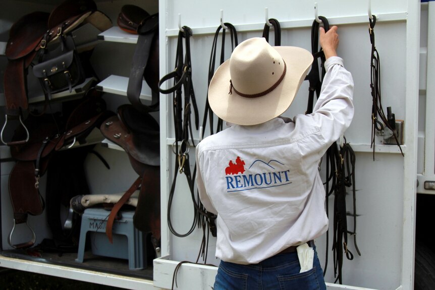 A horse owner packs up her horse's saddle