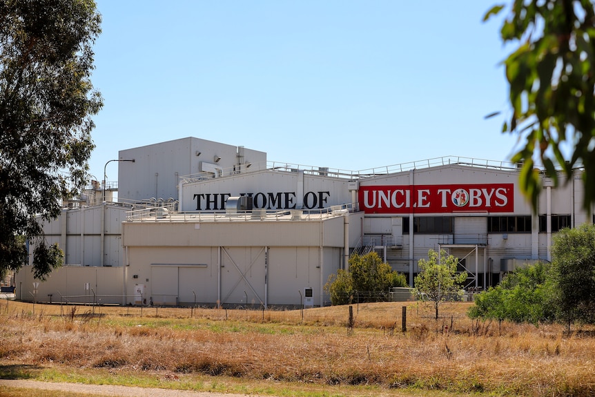 White factory in dry country landscape with painted sign that reads The Home of Uncle Toby's