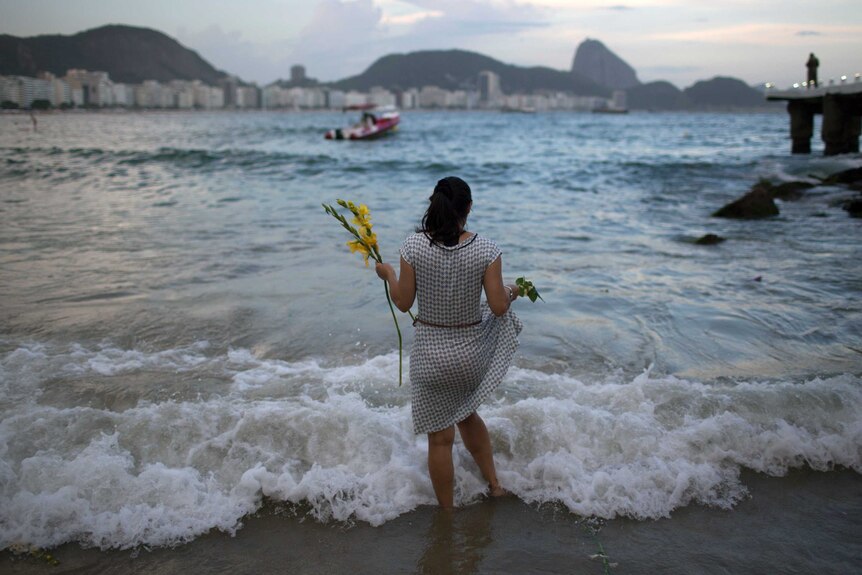 A woman in Rio offers flowers to Yemanja, goddess of the sea