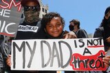 Man and two girls hold signs denouncing racism against black people