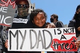 Man and two girls hold signs denouncing racism against black people