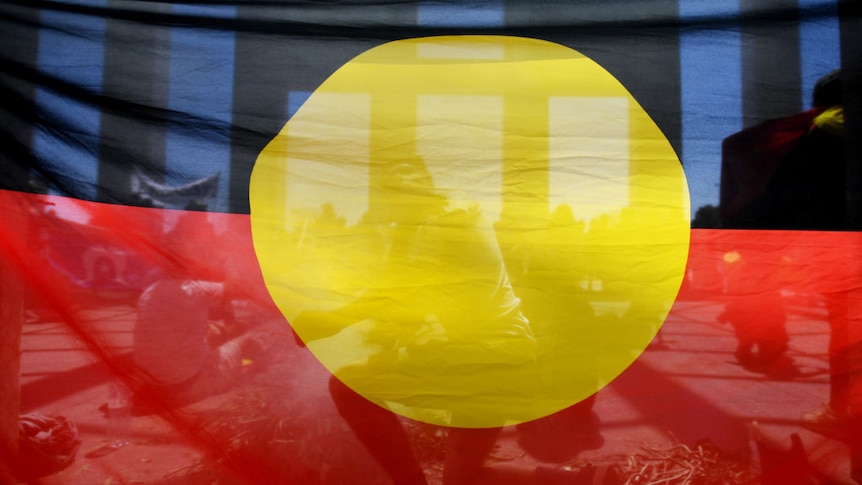 Australian Aboriginal flag held up in front of Canberra's Parliament House.