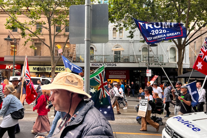 Protesters march through the Melbourne CBD holding flags and signs