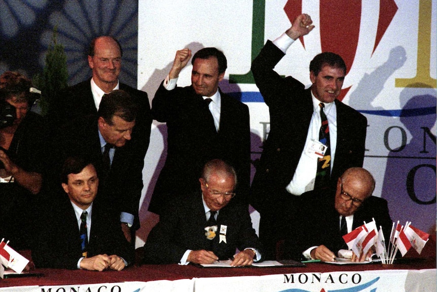 Men in suits celebrate winning the Sydney Olympic bid.